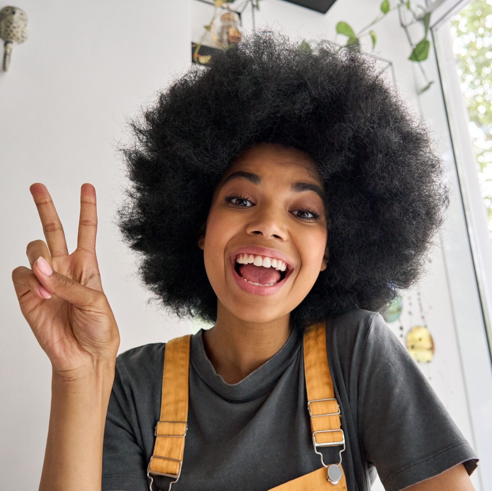 A cheerful Gen Z person with an afro hairstyle making a peace sign gesture on TikTok.