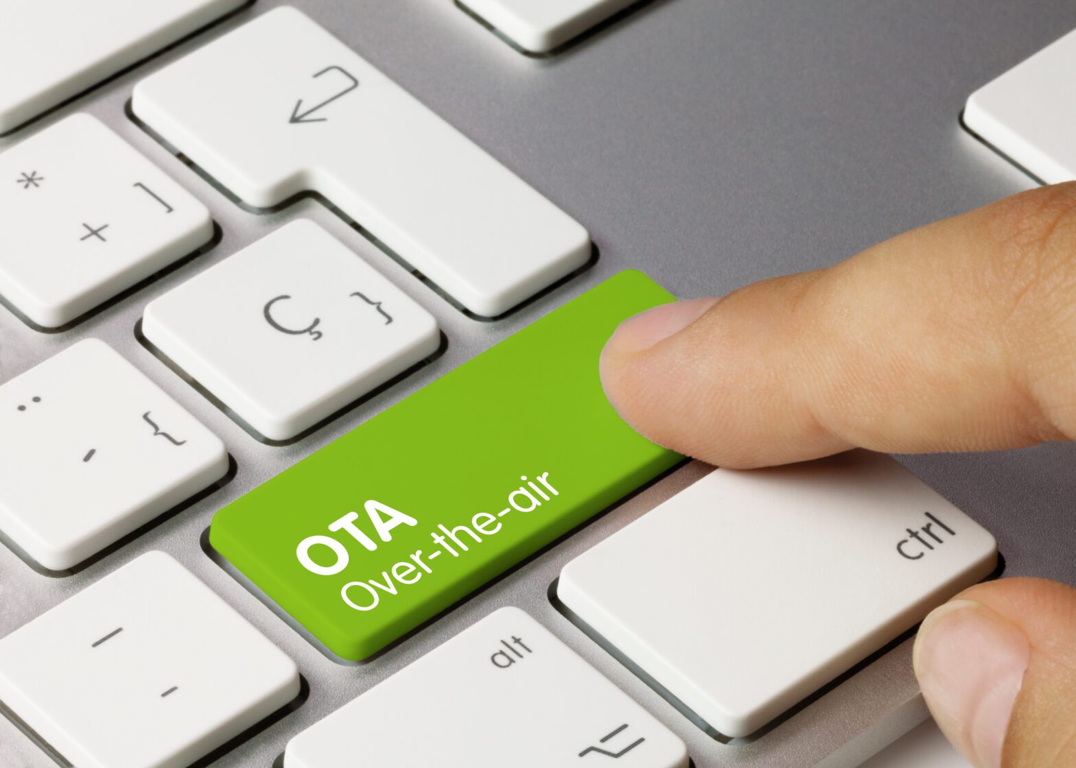 Finger pressing a green OTA advertising key on a computer keyboard.