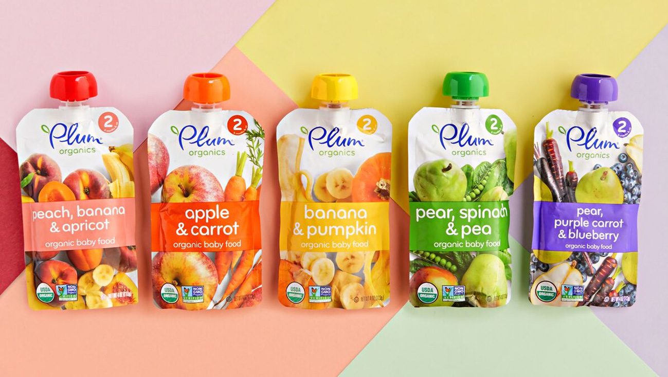 Five pouches of Plum Organics baby food are displayed on a colorful background, each showcasing flavors like peach, banana & apricot; apple & carrot; and more. Discover these delicious options on the Plum Organics website. A real parenting choice that creates a genuine connection in every family life moment.