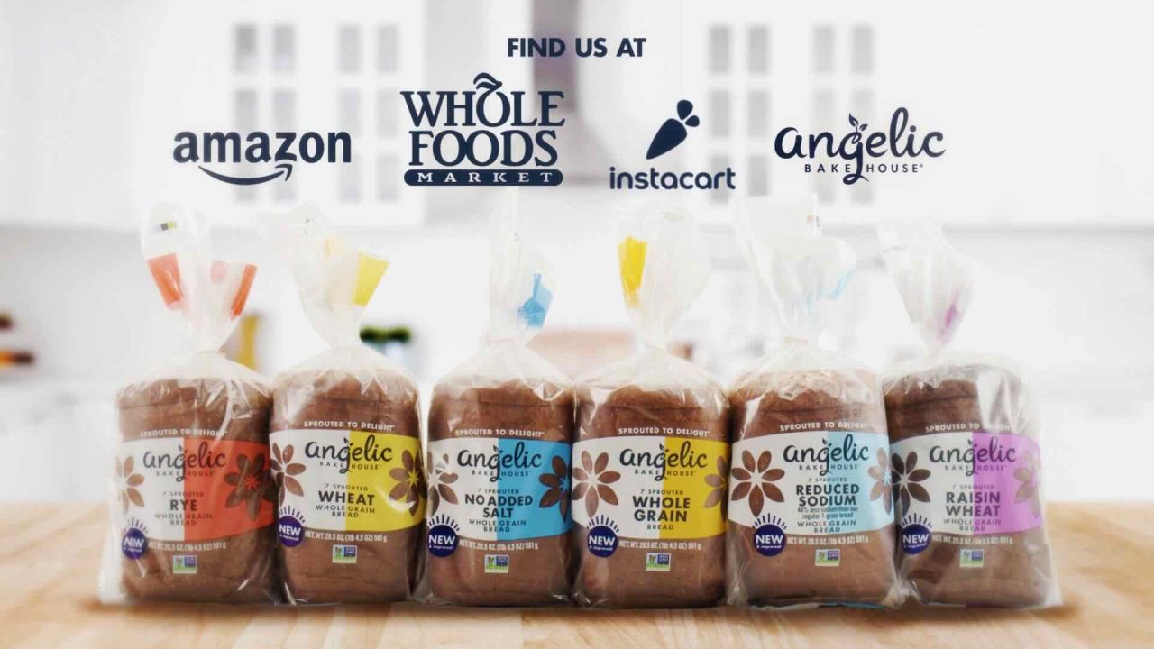 A display of six varieties of Angelic Bakehouse bread loaves in plastic packaging. Logos of Amazon, Whole Foods Market, Instacart, and Angelic Bakehouse are shown at the top—a perfect scene for the Angelic Bakehouse #BreadBod campaign's digital strategy and social media influencer partnerships.