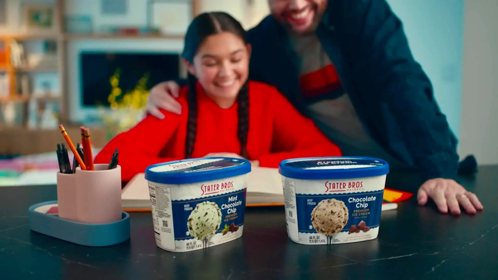 Two tubs of Stater Bros. ice cream are placed on a table, one labeled Mint Chocolate Chip and the other Chocolate Chip. A smiling man and girl are in the background, embodying the spirit of family celebrations and community commitment that Stater Bros. Markets brings to Southern California milestones.