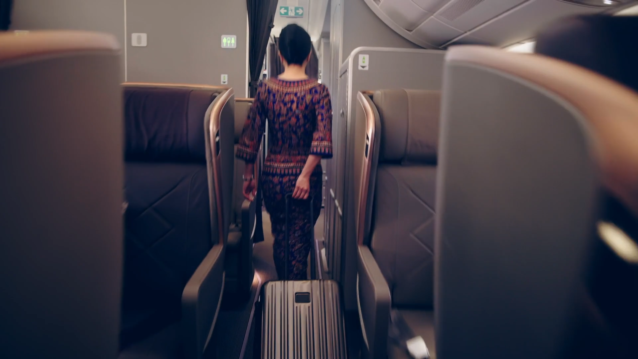 A flight attendant walks down the aisle of a Singapore Airlines Airbus A350-900 ultra-long-range aircraft, ensuring that travelers enjoy a non-stop travel experience from New York to Singapore. The luxury business class service and onboard dining options cater exceptionally well to both business and leisure travelers.
