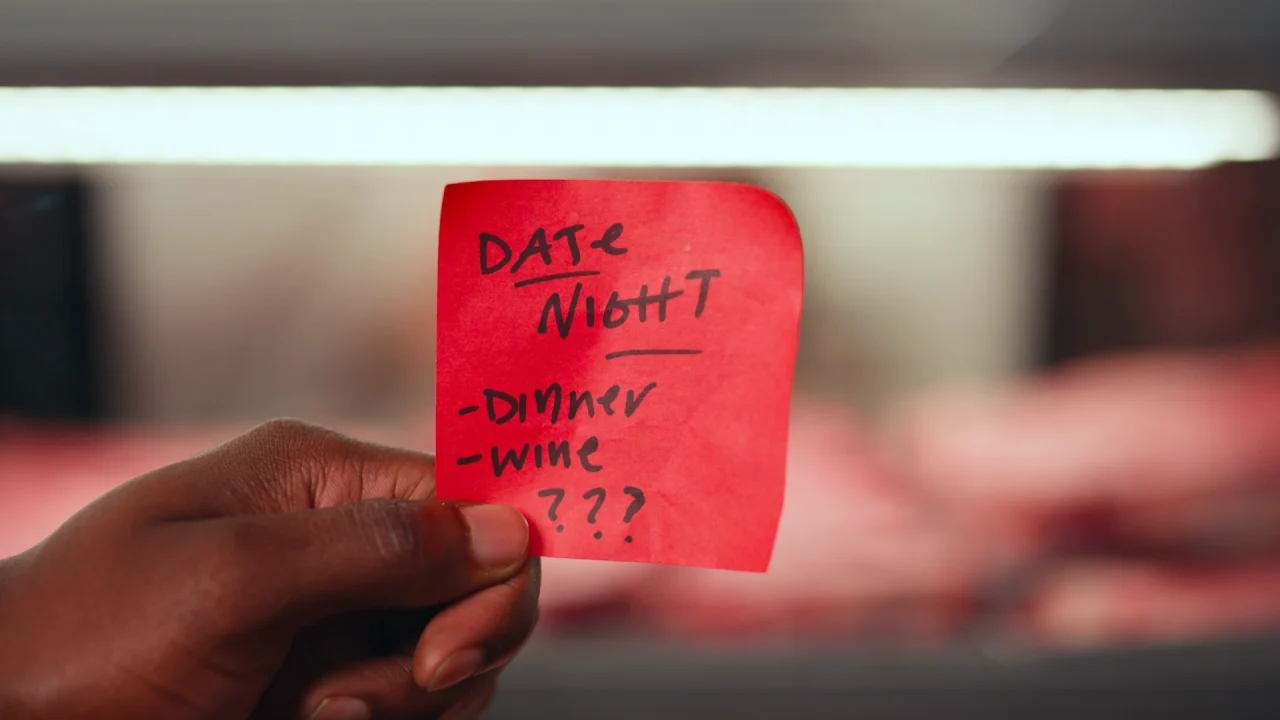 A hand holds a red sticky note with "DATE NIGHT" written at the top followed by a list: "Dinner," "Wine," and three question marks, setting the perfect scene for a B2C grocery commercial production.